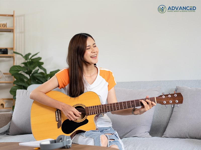 A young woman practising basic guitar chords and playing guitar