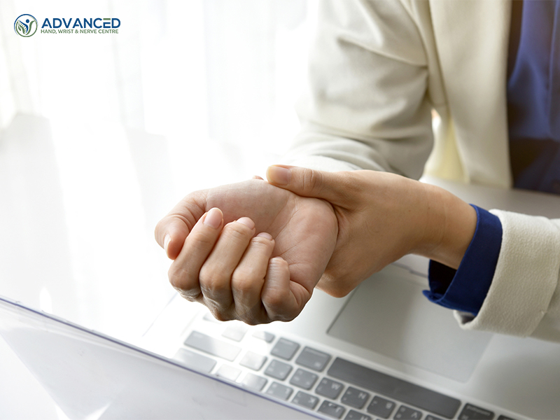 Closeup of woman holding her wrist pain from using a laptop computer long time