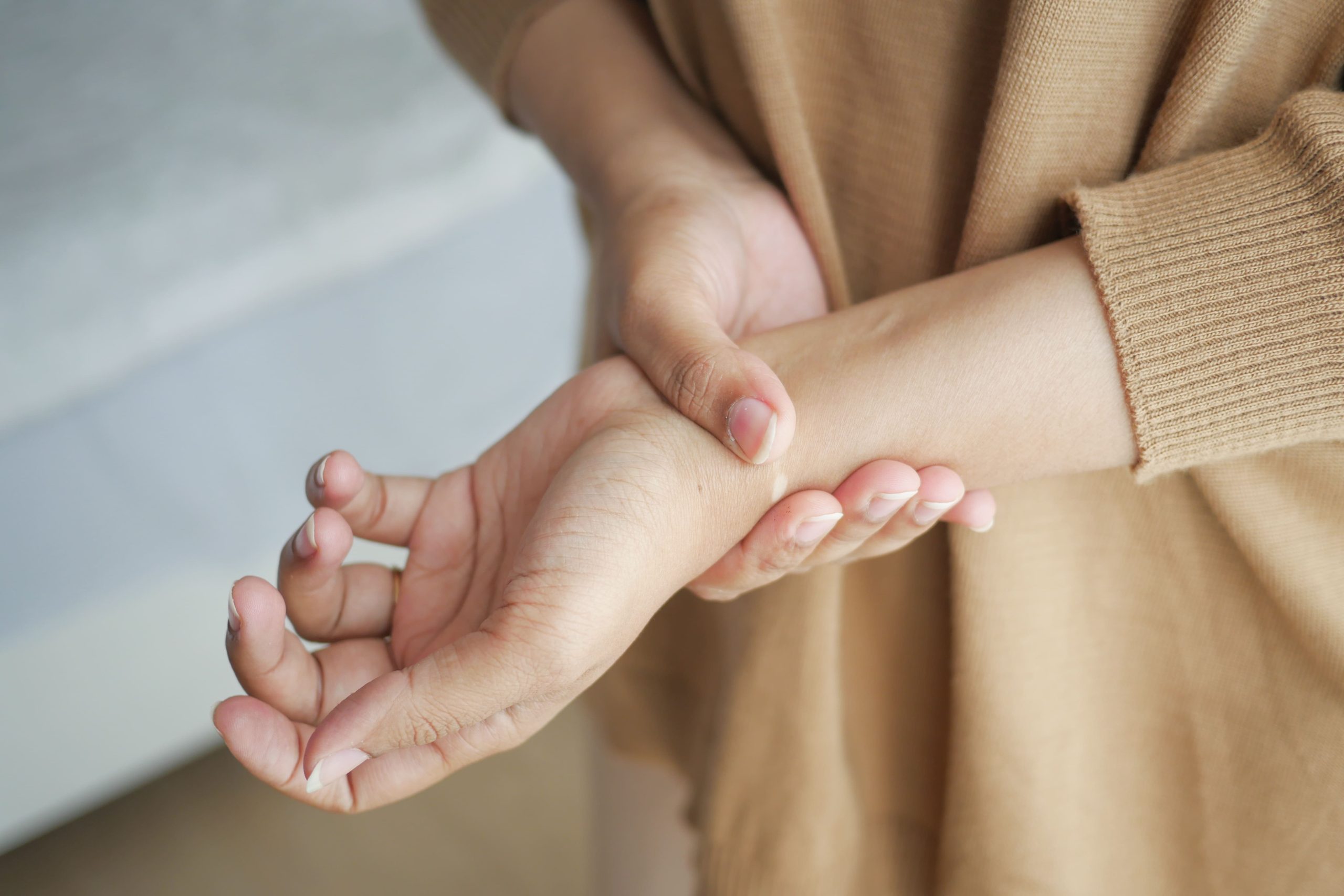 An adult person holding their wrist in a home setting.
