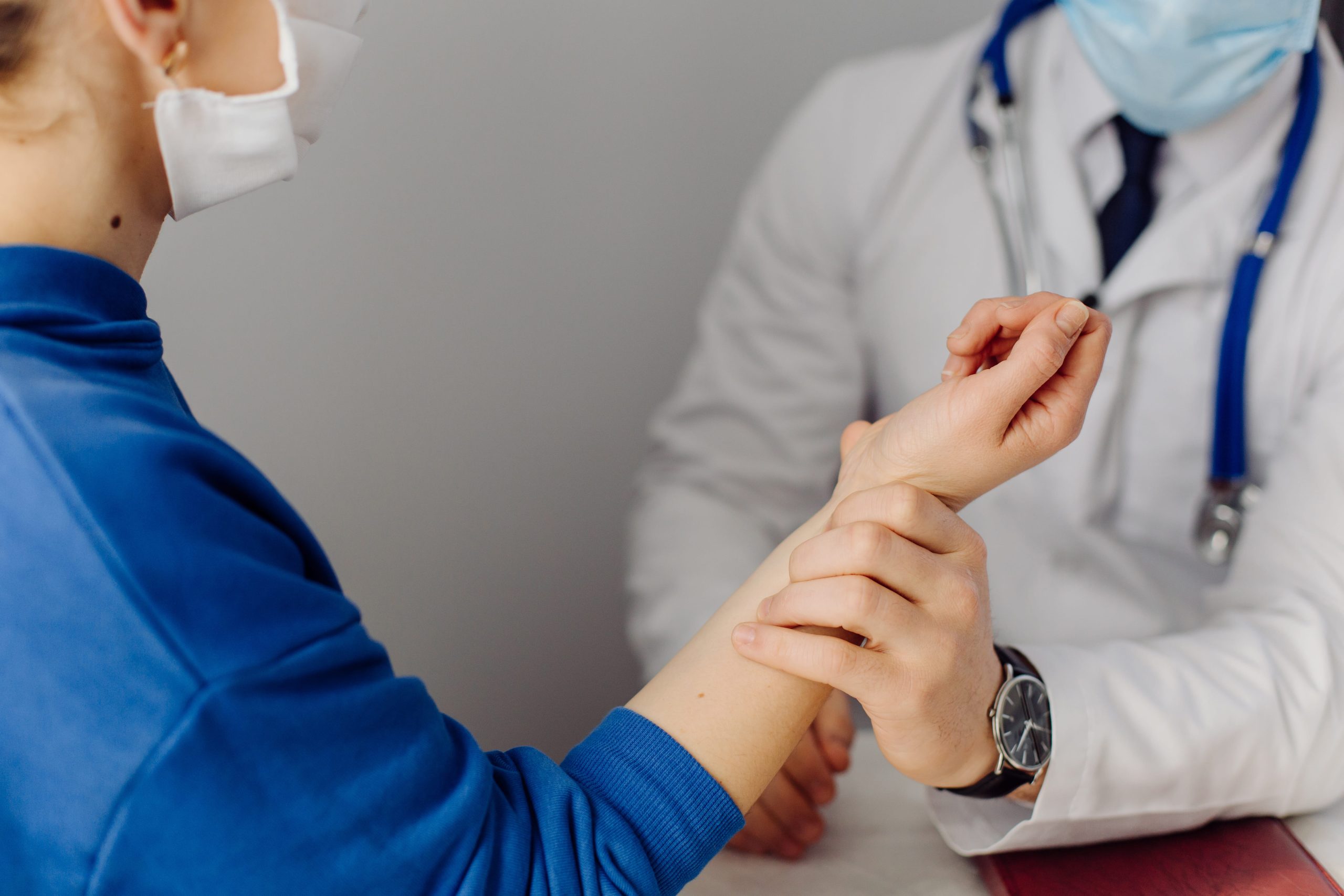 A healthcare professional examining a patient's wrist during a medical consultation.
